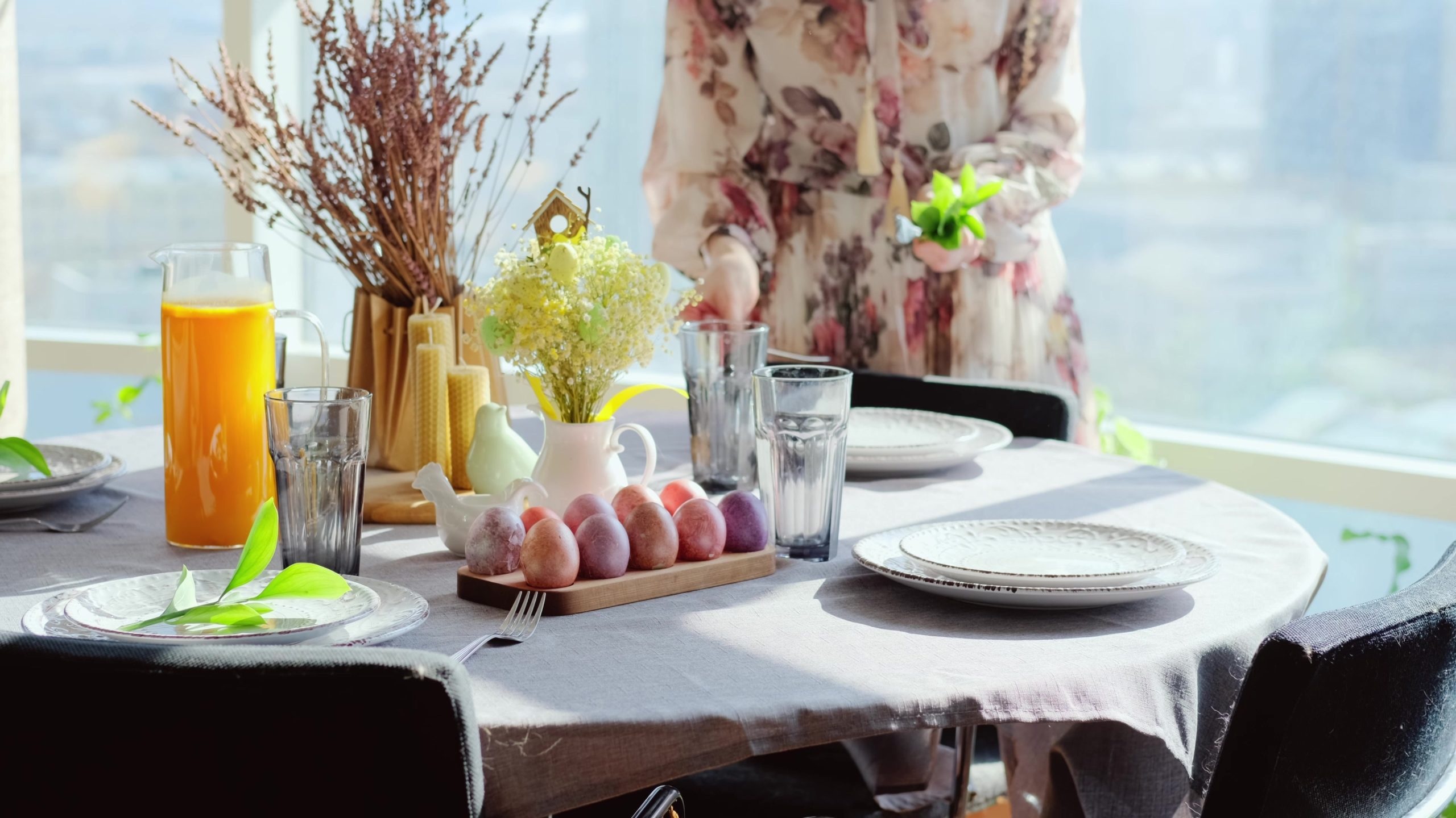A woman in a smart dress serves a festive Easter table