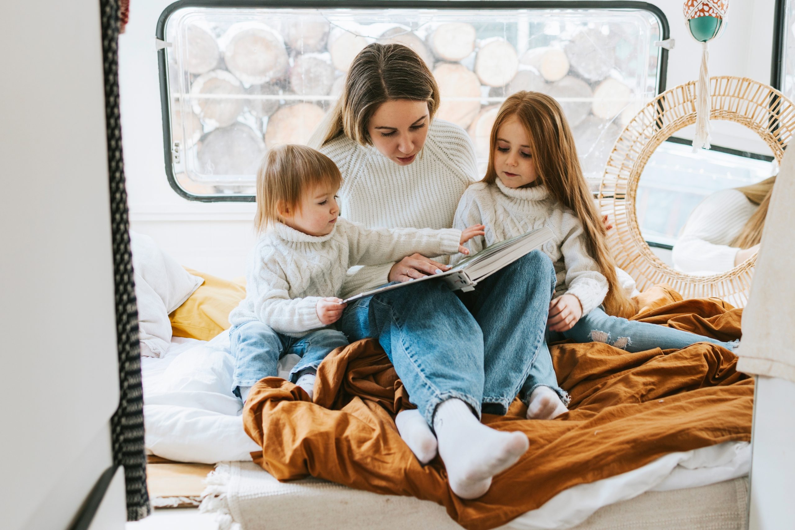 family reading camping book for kids in cosy bed in trailer mobile home 
