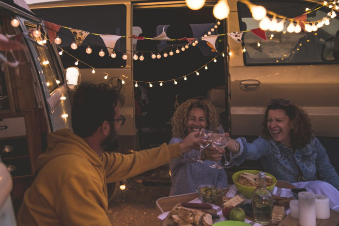 happyfriendscheeringanddrinkingwineduringcampingvacationat